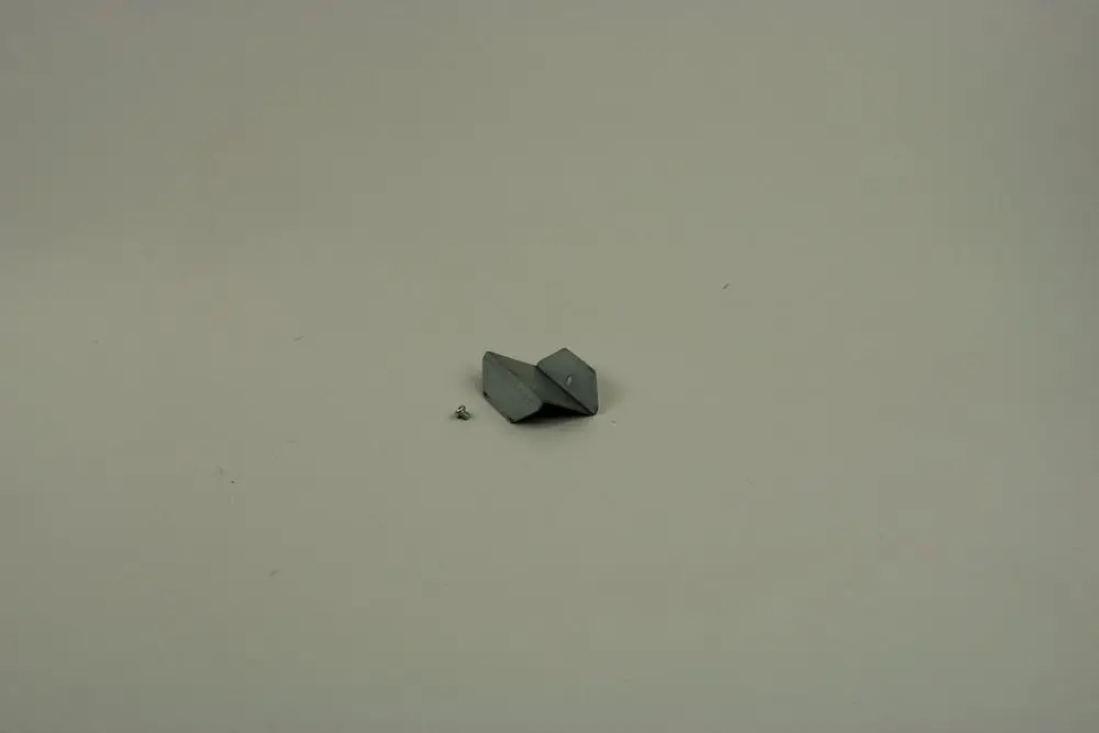 BOSCH Haltewinkel aus Metall in grauer Farbe, mit einer flachen, trapezförmigen Form und einem kleinen zylindrischen Element daneben auf einer neutralen Oberfläche.